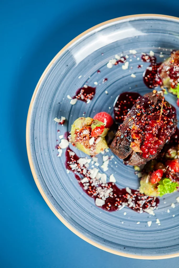 Plat-de-viande-servi-au-restaurant-Le-Parvis-à-Cholet Plat de viande servi dans une assiette bleue au restaurant Le Parvis à Cholet.